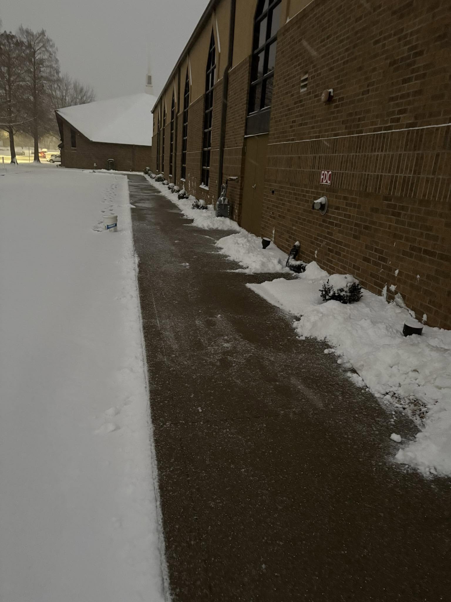 Snow-cleared walkway beside brick building